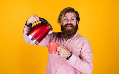one more cup. brutal handsome man with moustache drink tea. mature man husband hold electric kettle. modern technology in life. bearded hipster use home appliances. kitchen conceptの写真素材