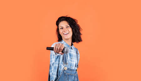 smiling female hipster with trendy clothes sing in microphone, music