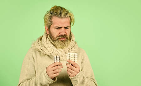 Immune system fight infections. Bacteria invades body. Virus treatment. Bearded hipster messy hairstyle. Sick man hold tablets. Virus pneumonia. Buy medicines. Virus fever. Vitamin supplementsの写真素材