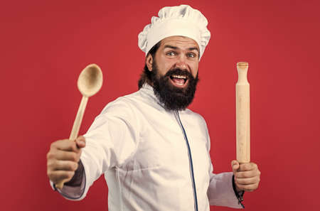 hipster chef in hat with beard and moustache on red background use wooden kitchne utensil, cookingの写真素材