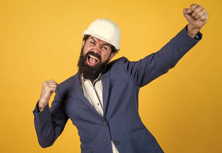 concept of engineering. architecture and building. male builder wearing formal suit and helmet for protection. working on construction project. happy man with beard wear hard hatの写真素材