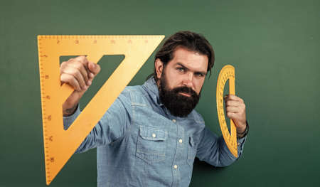 formal education. male student at mathematics school lesson. pass the math exam. learning the subject. serious man with beard using triangle ruler. studying the measurementの写真素材