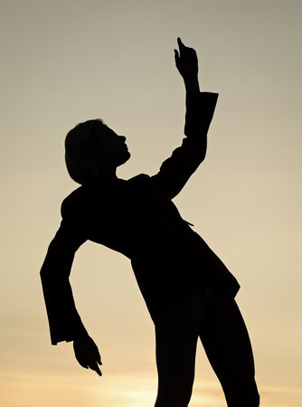 carefree. female silhouette on sunset. woman dance in sunrise. dark figure of dancer.の写真素材