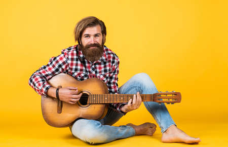hipster man playing the acoustic guitar. country music style. man wearing checkered shirt and holding guitar. play string musical instrument. professional caucasian musician. guitaristの写真素材