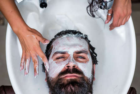 Hairdresser washes client man head in barbershop and use foam cream, hair careの写真素材
