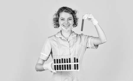 Test your blood. scientist in face mask and gloves holding test tube with red substance....