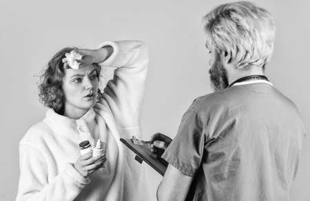 patient and doctor hold pills. woman with runny nose at nurse consultation. doctor write...