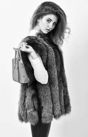 Woman in fur coat with handbag on white background. Girl fashion lady stylish hairstyle wear mink fur coat. Fashion stylish accessory. Fashion and shopping concept. Female fashion model hold purseの写真素材