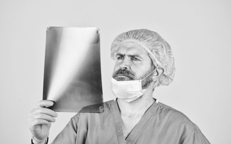 surgeon doctor examines radiographical snapshot. x-raying of vertebra. health problems. nurse checking x-ray film at hospital. Experienced male doctor interpretate X-ray. man look at roentgenの写真素材