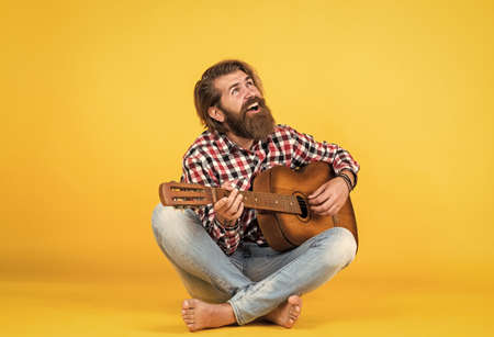 fing the melody. play string musical instrument. professional caucasian musician. guitarist. hipster man playing acoustic guitar. country music style. man wearing checkered shirt and holding guitarの写真素材