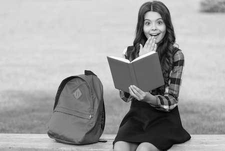 Finding inspiration in reading. Surprised child read book sitting on park bench. Inspiration concept. School library. Literacy education. Just inspiredの写真素材