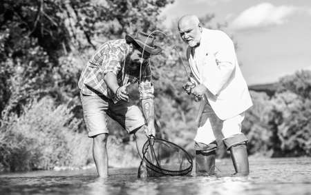 Nothing but family. happy fishermen friendship. Two male friends fishing together. Catching and fishing concept. fly fish hobby of businessman. retirement fishery. retired dad and mature bearded sonの写真素材
