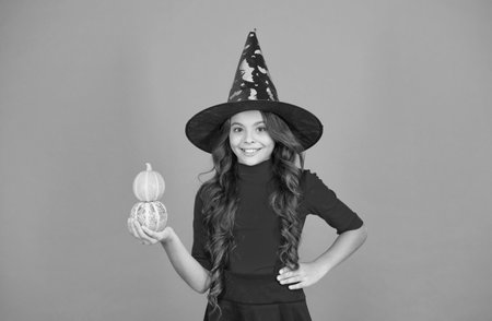 all you need is pumpkin. child celebrate autumn holiday. teenage girl in witch hat celebrate party. happy halloween. trick or treat. carnival festive costume of witch. kid with small pumpkinの写真素材