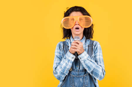woman singing with microphone in karaoke. young hipster TV reporter is broadcasting. singer with microphone. presenting an event. happy girl enjoy the moment. Have Fun on Celebration. copy spaceの写真素材