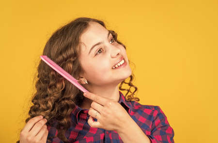 Brushing long hair. Enjoying shiny curls. Balm oil conditioner for styling. Little child curly hair. Hairstyle for party. Hairdresser supplies. Fashion and beauty. Small girl hairdresser salonの写真素材