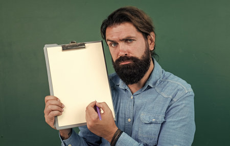look here. mature bearded teacher with document folder. brutal man work in classroom with blackboard. prepare for exam. college lecturer on lesson. back to school. formal education. knowledge dayの写真素材