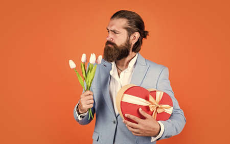 Best Valentines Day. bearded man in elegant jacket hold flowers. wedding day. happy valentines day. bride groom with bouquet and box. hipster man hold tulip flowers. love gift for romantic dateの写真素材