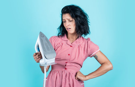 cant live without it. unhappy housekeeper ironing. concept of householding. steaming iron. pinup girl prepare ironing. lady hold modern iron. Everyday life and housework. retro woman with ironの写真素材