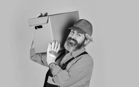 Service delivery. Delivering purchase. Shopping. Bachelor day. Post worker. Delivered to your destination. Courier and delivery. Postman delivery worker. Handsome man red cap yellow backgroundの写真素材