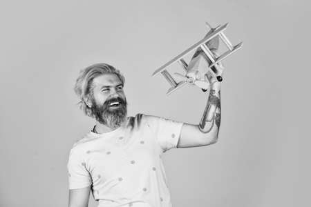 nice trip. aeromodelling. handmade toy shop. lets fly. feel the freedom. happy carpenter. bearded man play with wooden plane. dream about summer vacation. mature pilot orange backgroundの写真素材