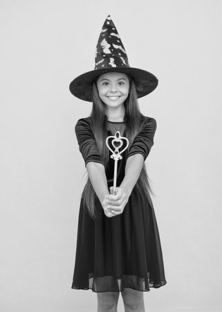 halloween witch girl. happy childhood. teenage child in witch hat. cheerful kid create miracles with magic wand. carnival costume party. trick or treat. celebrate the holidaysの写真素材