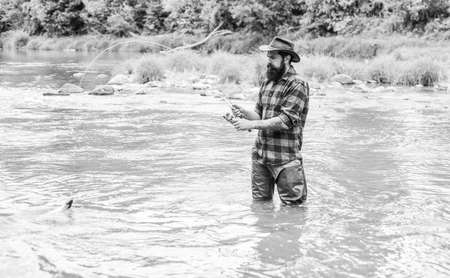 Your Favourite hobby. bearded fisher in water. hobby and sport activity. fisherman show fishing technique use rod. mature man fly fishing. man catching fish. summer weekend. Happy fly fishingの写真素材