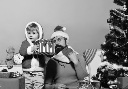 Santa and little assistant among gift boxes near Christmas tree.の写真素材