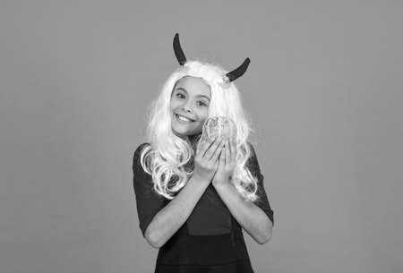 happy kid with long wig hair wear devil horns hold pumpkin vegetable making jack o lantern for...