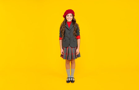 happy teen girl in uniform and beret on yellow background, fashionの写真素材