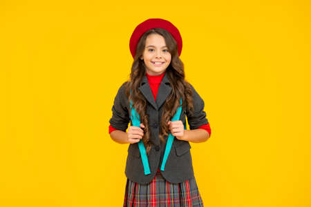 cheerful kid in school uniform with beret and backpack on yellow background, pupilの写真素材