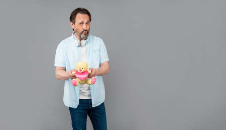 Senior man air kiss holding teddy bear with heart grey background copy space, valentines dayの写真素材