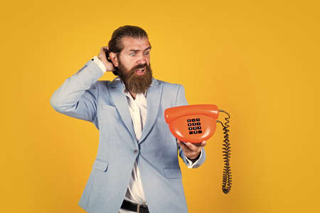 Get your phone fixed today. line is busy. Fellow On The Phone. young man talking on telephone. businessman talking on vintage phone. Male talking on landline phone. vintage technology in modern lifeの写真素材
