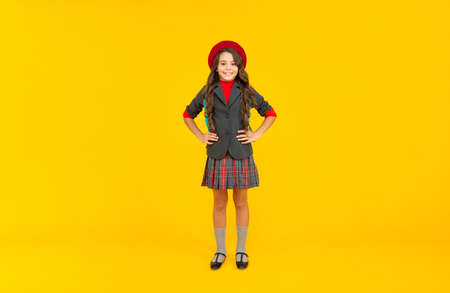 positive child in school uniform and beret full length on yellow background, pupilの写真素材