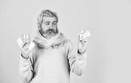 Unhealthy man holding pills and water glass. Medication and increased fluid intake. cough cold and runny nose remedy. you need to be strong. Tolerating the drug well.の写真素材