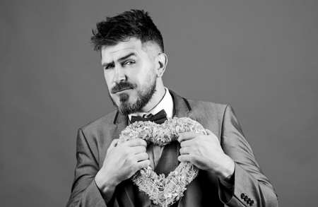 pain in heart. businessman in bow tie has heart problems. Love. Wedding day. stylish esthete with decorative heart. Valentines day holiday. bearded man in formal suit. heart failure. Love and romanceの写真素材