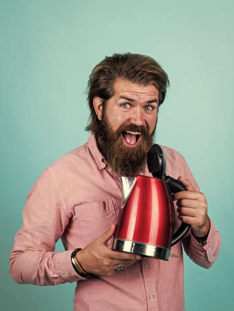 his choise. happy hipster with moustache boil water. male householding. tea drinking concept. bearded man in shirt hold electric kettle. casual guy use modern technology in everyday lifeの写真素材