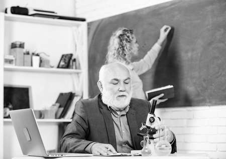 Student study. Educator and student classroom. Girl with notepad near chalkboard. High school college university education. STEM concept. Man bearded professor teaching student. Educational activityの写真素材