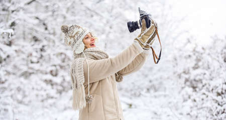 Cheerful winter girl. winter girl with vintage camera. happy woman make selfie on camera. winter selfie. having fun outdoor snowy forest. cold weather brings good mood. ready for weather forecastの写真素材