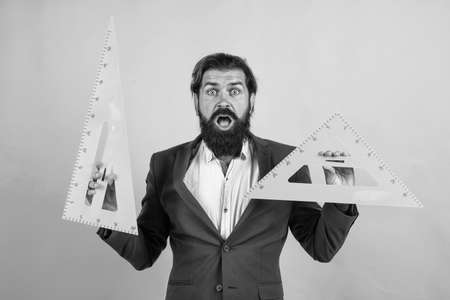 college lecturer on geometry lesson. back to school. formal education. knowledge day. mature bearded teacher use math ruler tools. brutal man work in classroom with triangle. prepare for examの写真素材