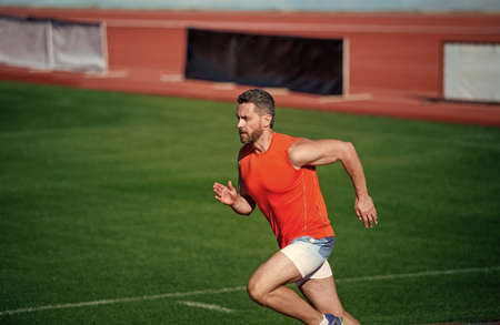 energetic athletic muscular man runner running outdoor on green grass, staminaの写真素材
