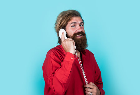 conversation. modern looking bearded hipster speaking on phone. communication concept. brutal handsome man with moustache use vintage phone. mature manager or assistantの写真素材