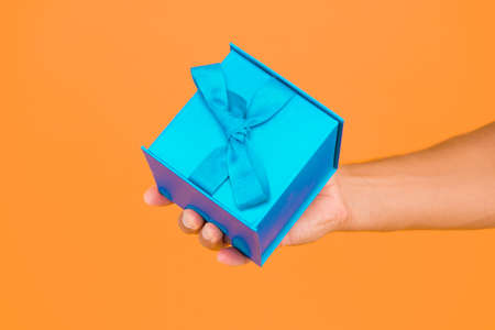 Gift shop concept. Making surprise for her. Celebrate valentines day. Valentines day gift. Gift for girlfriend. Romantic gift. Gift box in male hand yellow background. Love romantic feelings conceptの写真素材