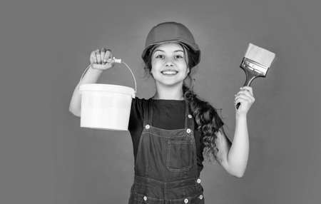 happy kid engineer with painting bucket and brush tool in hard hat, hobby