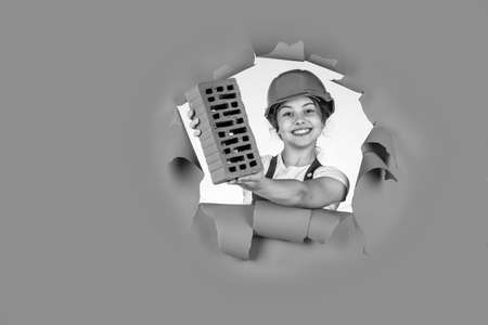 teen girl builder in protective helmet use brick, buildingの写真素材