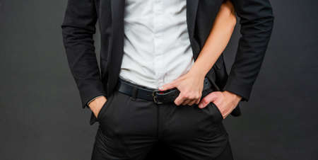 female hand on male belt on black background, loveの写真素材