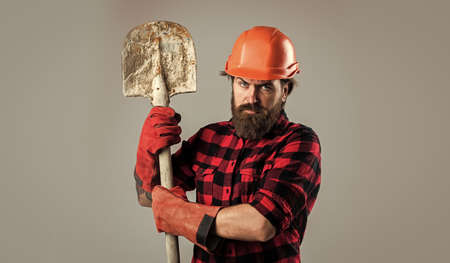 brutal man builder in uniform and helmet with shovel, architecture