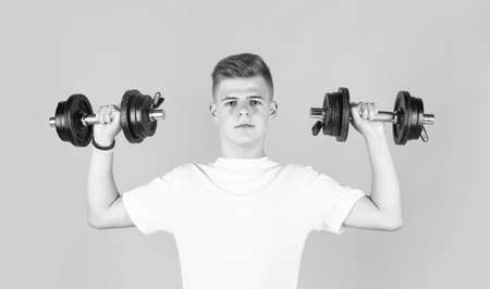 teen boy training biceps muscles with barbell, sportの写真素材