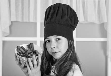 small girl in cook hat hold plate with spices, recipeの写真素材