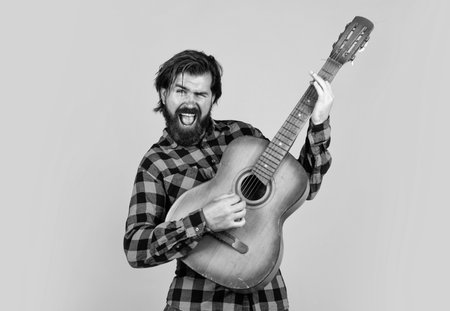 brutal bearded male with stylish look playing acoustic guitar, music