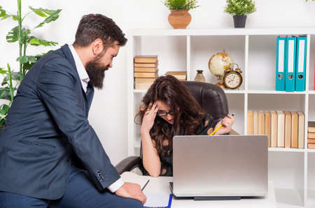 Serious office manager working while boss sitting on office desk, professionalsの写真素材